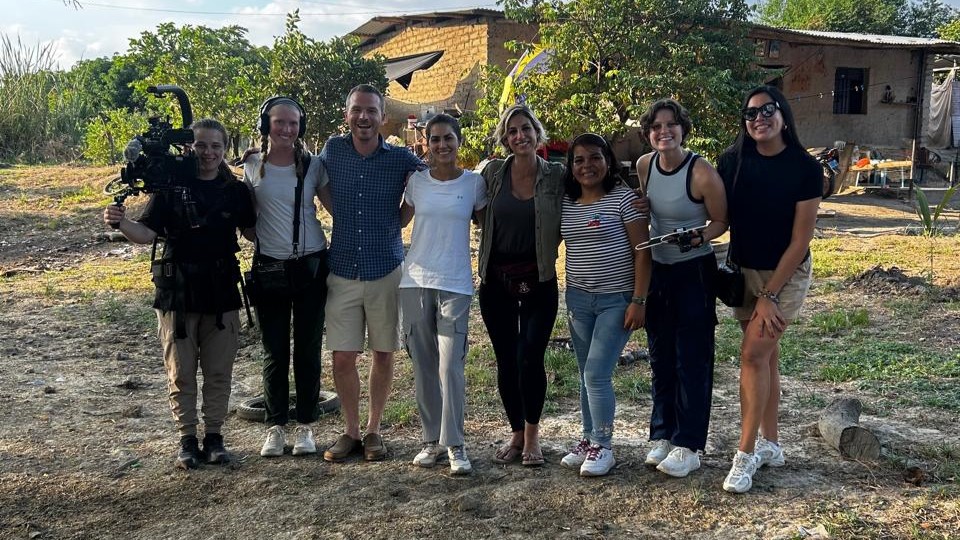 Documentary team poses with cameras in front of a sky